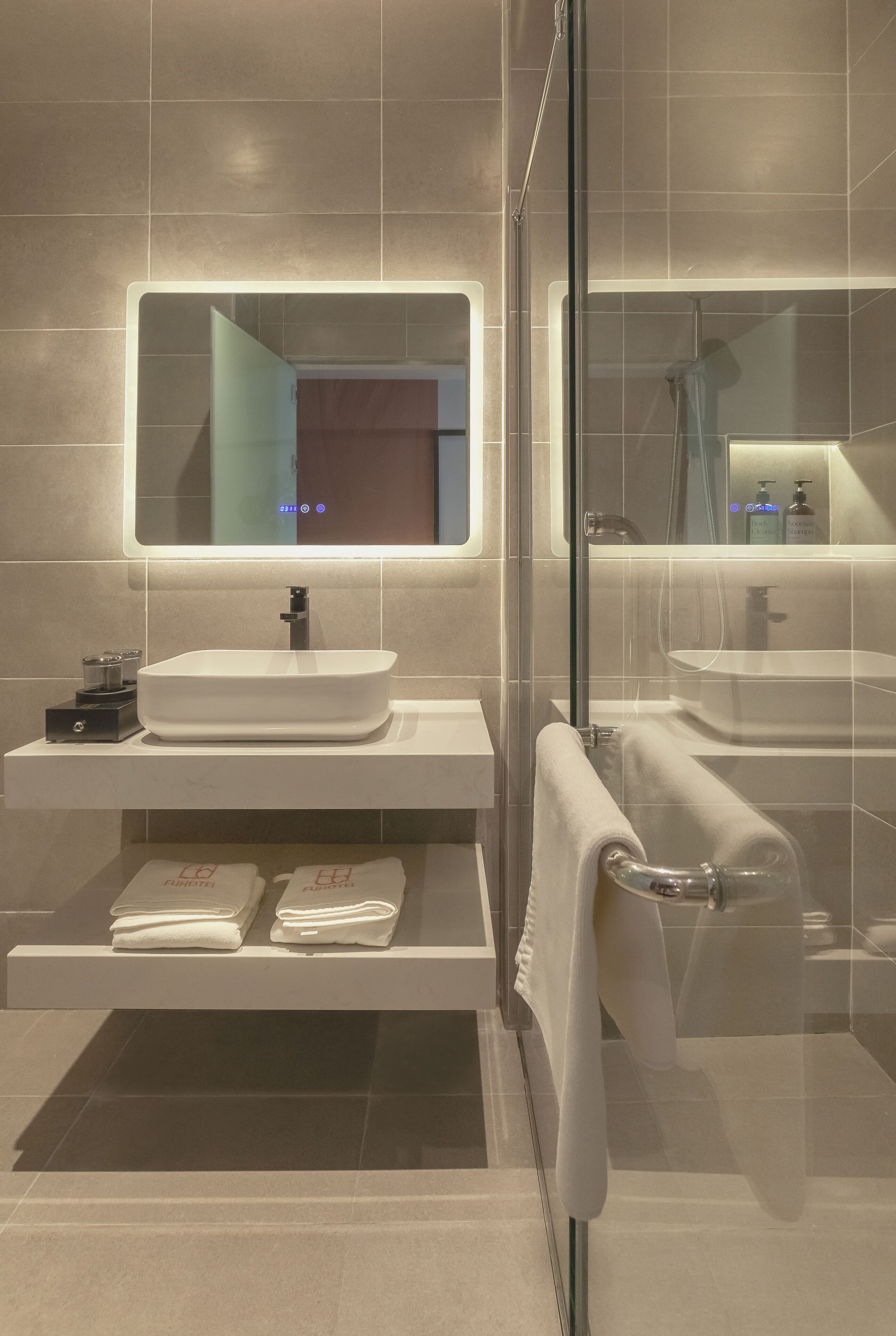 A modern bathroom with a large mirror, a white sink, and a glass shower enclosure.