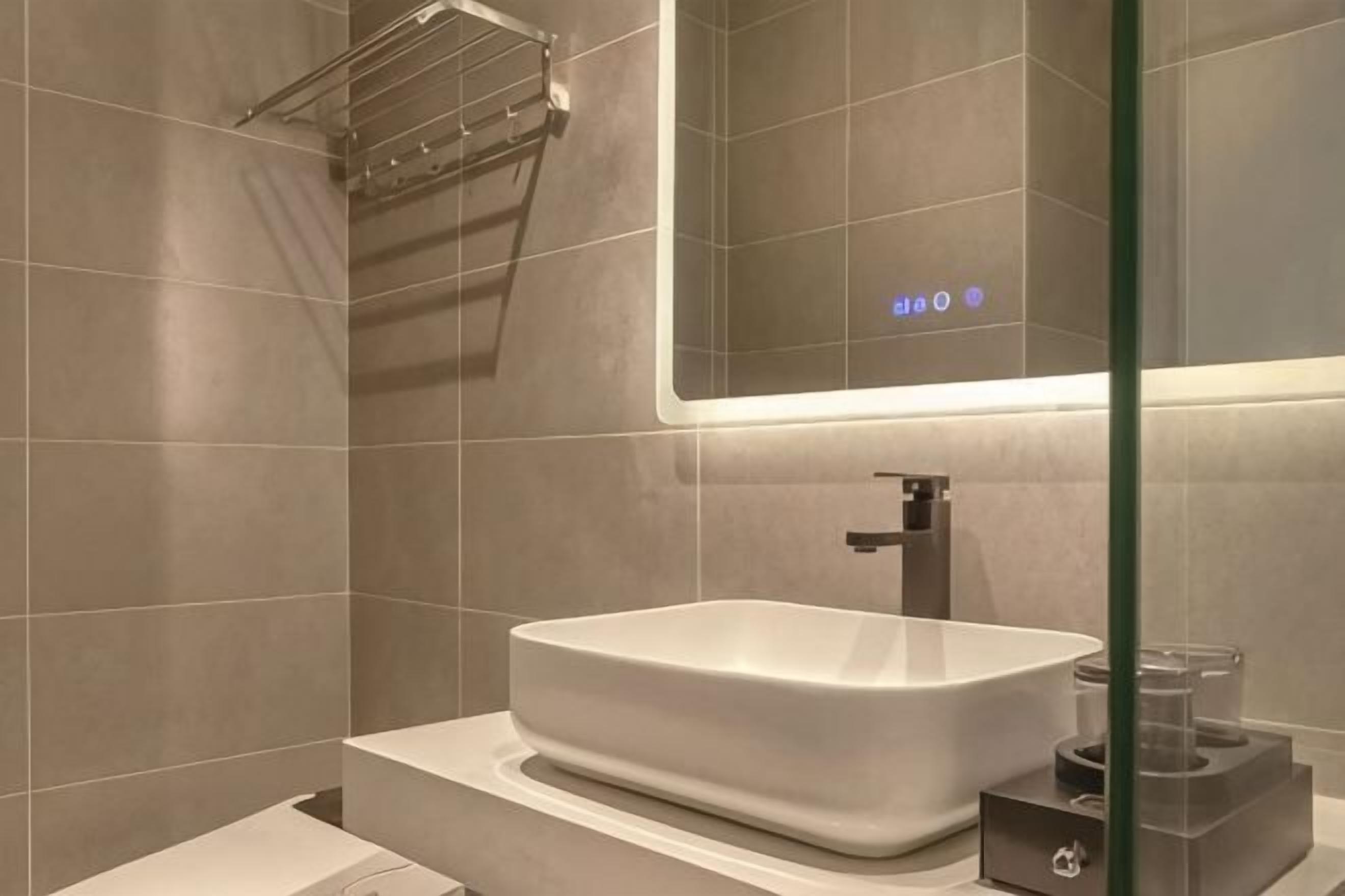 A modern bathroom with a large rectangular sink, a mirror, and a towel rack.