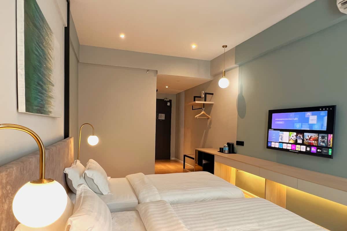 Een moderne hotelkamer met een groot bed, bedlampjes, een aan de muur bevestigde televisie en een klein bureau.