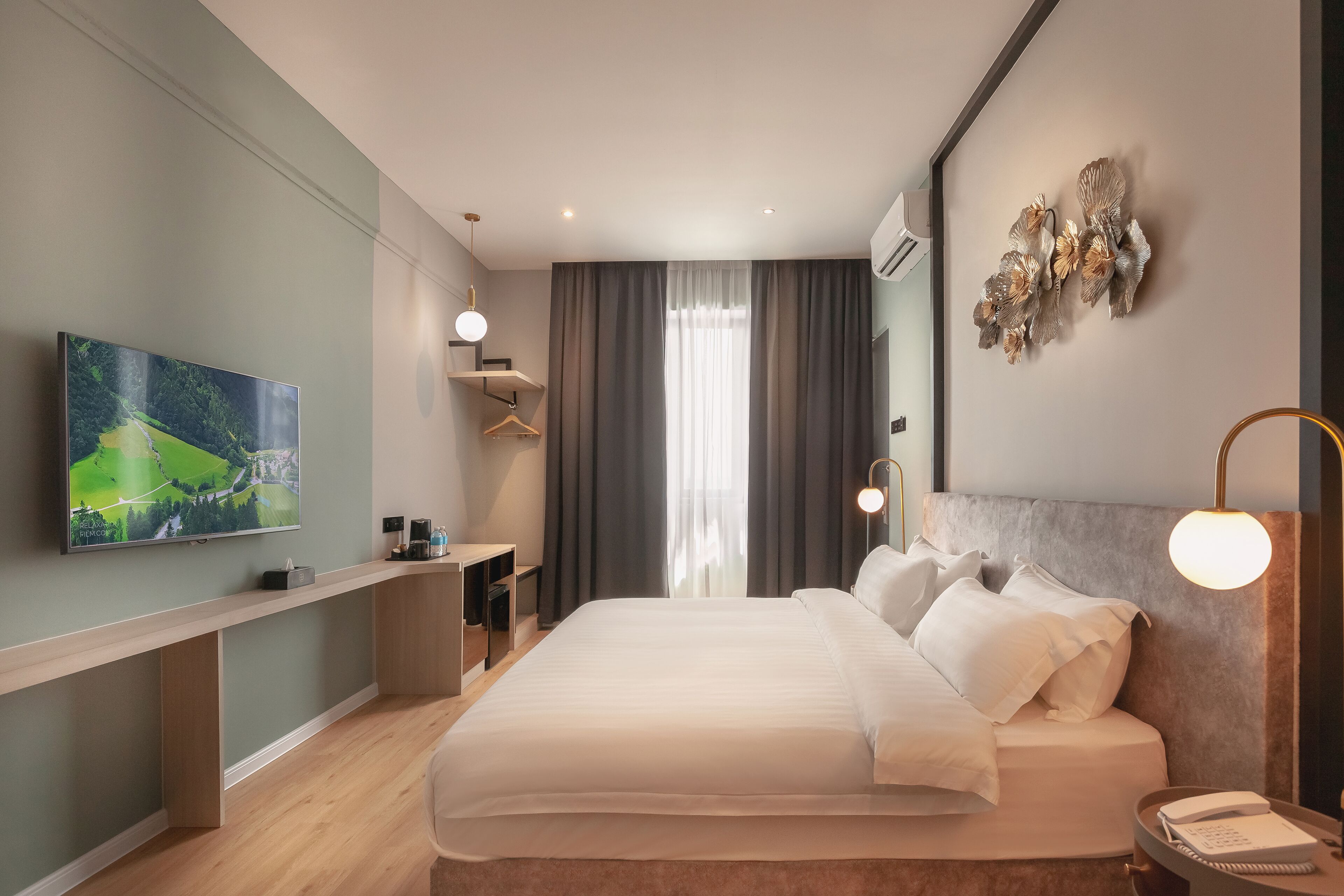 Habitación de hotel moderna con una cama grande, un televisor de pantalla plana, un escritorio y una obra de arte colgada en la pared.
