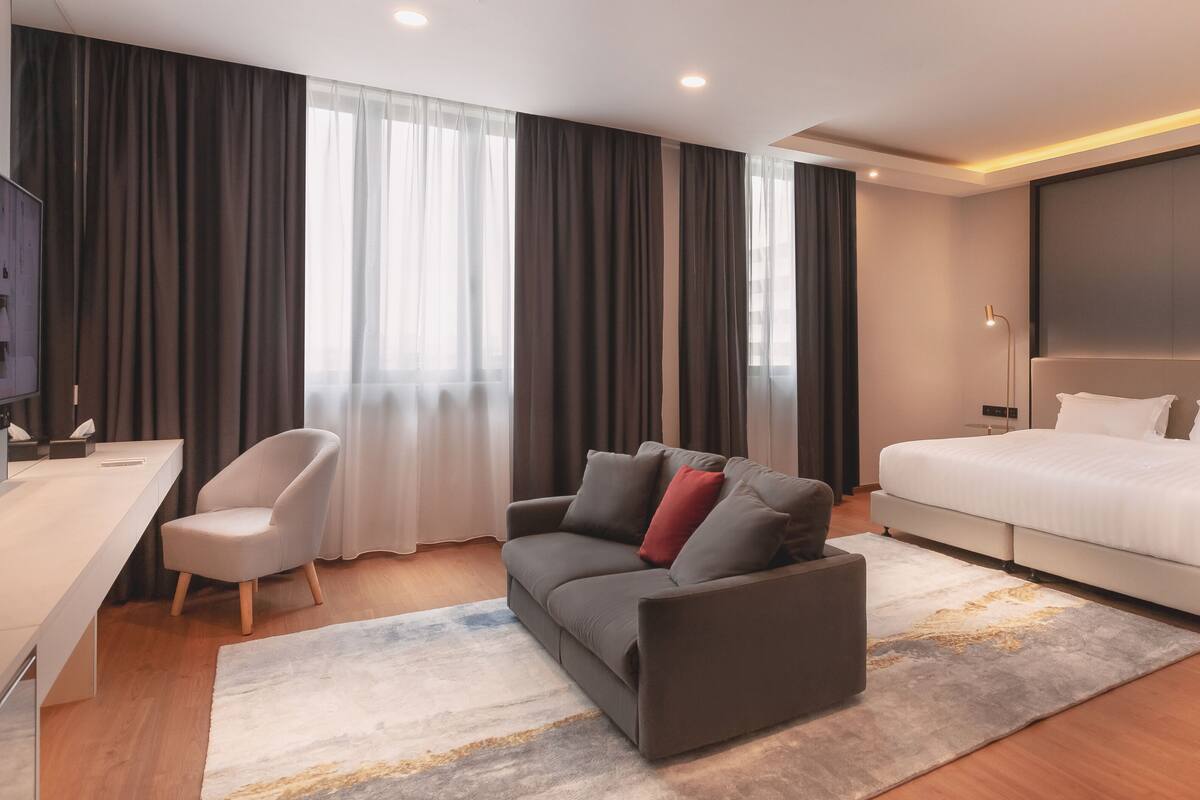 Een moderne hotelkamer met een bed, een bank, een bureau en een televisie.