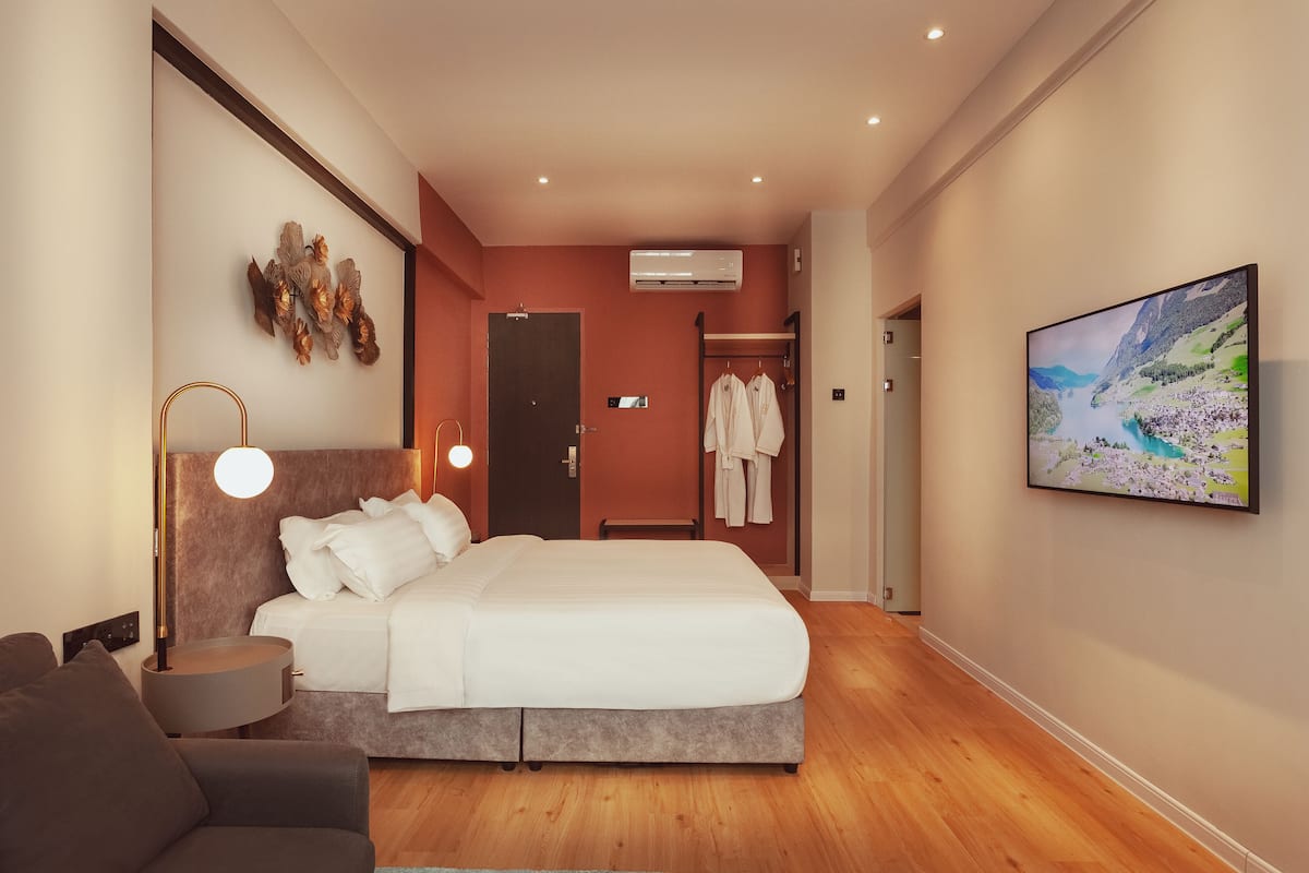 Een moderne hotelkamer met een groot bed, een bedlampje, een flatscreen televisie en uitzicht op een bergachtig landschap.
