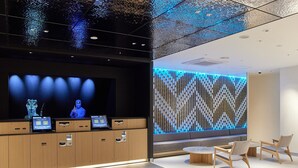 Een moderne receptiebalie met een digitaal scherm, houten kasten en een gestreept wanddecor.