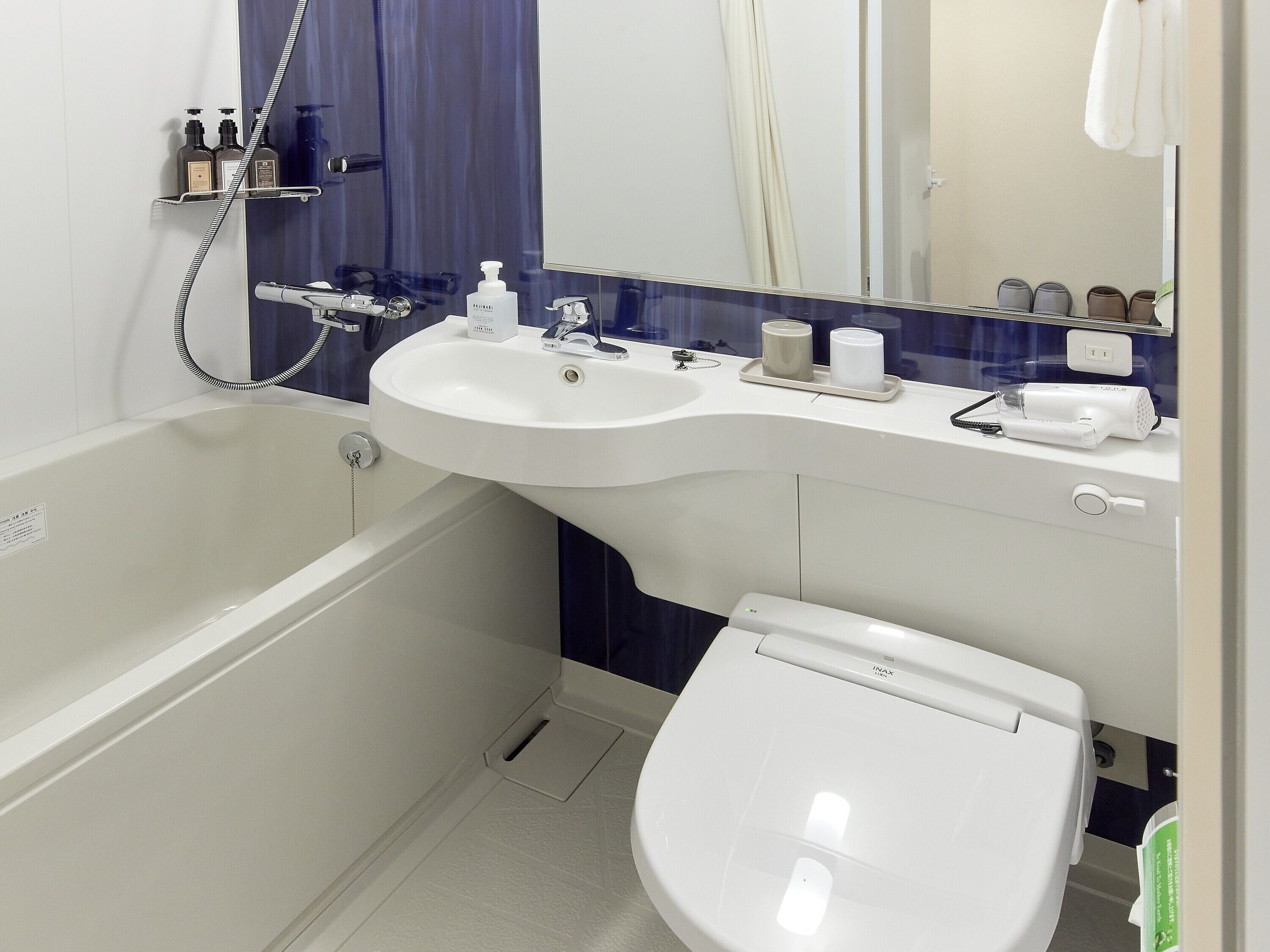 A modern bathroom with a bathtub, two sinks, a toilet, and a mirror.