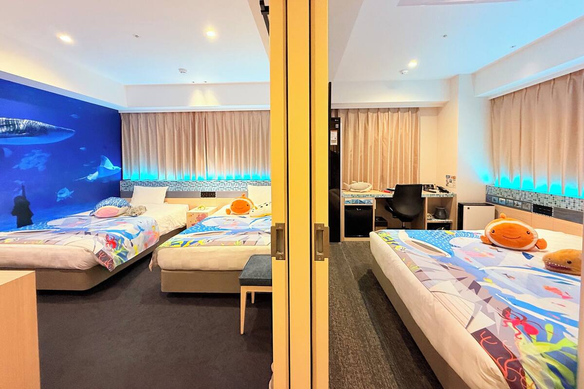 Une chambre d’hôtel avec deux lits, un bureau et une chaise.