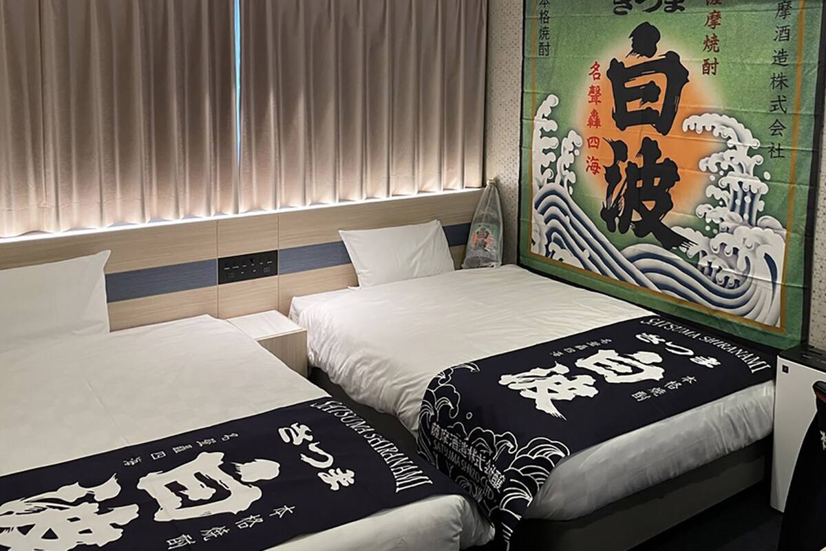 Une chambre d’hôtel avec deux lits, une grande affiche au mur et une fenêtre avec des rideaux.