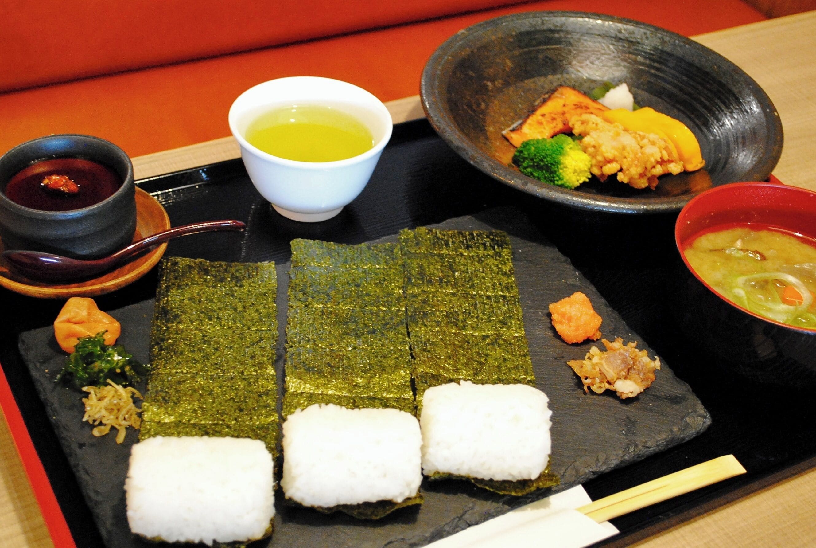 A tray with sushi, a bowl of soup, and a small dish of sauce.