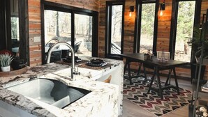 Una cocina con encimera de mármol, un fregadero y una zona de comedor con mesa y sillas.
