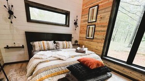 Un dormitorio con cama, un banco, una ventana y una pared de madera.