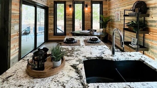 Una cocina con paredes de madera, encimera de mármol, un lavamanos y una lámpara en el techo.
