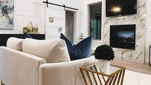 Una sala moderna con un sofá, una mesa de centro y un televisor montado en la pared.