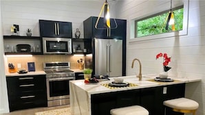 Una cocina moderna con una isla central, electrodomésticos de acero inoxidable y una ventana con vistas al verdor.