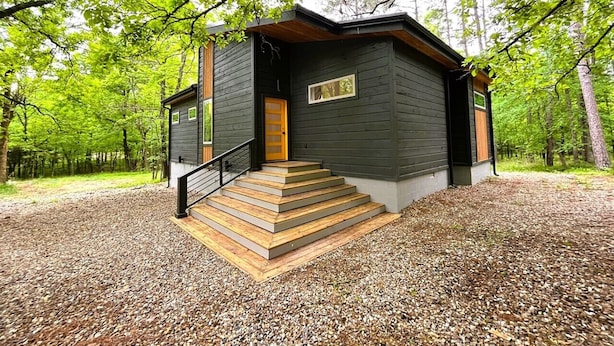 Una cabaña con una escalera de madera que lleva a una puerta, rodeada de árboles.