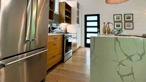 Cozinha moderna com eletrodomésticos de aço inoxidável, armários de madeira e uma ilha de mármore.