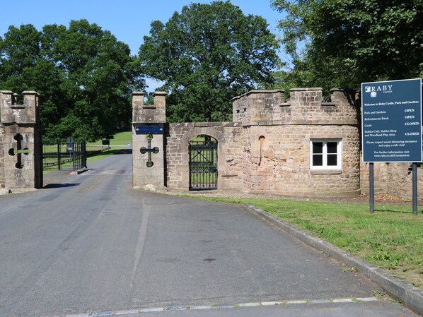 A stone gate with a sign indicating the entrance to a castle, park, and gardens. - 1 Claire House Way (Barnard Castle)