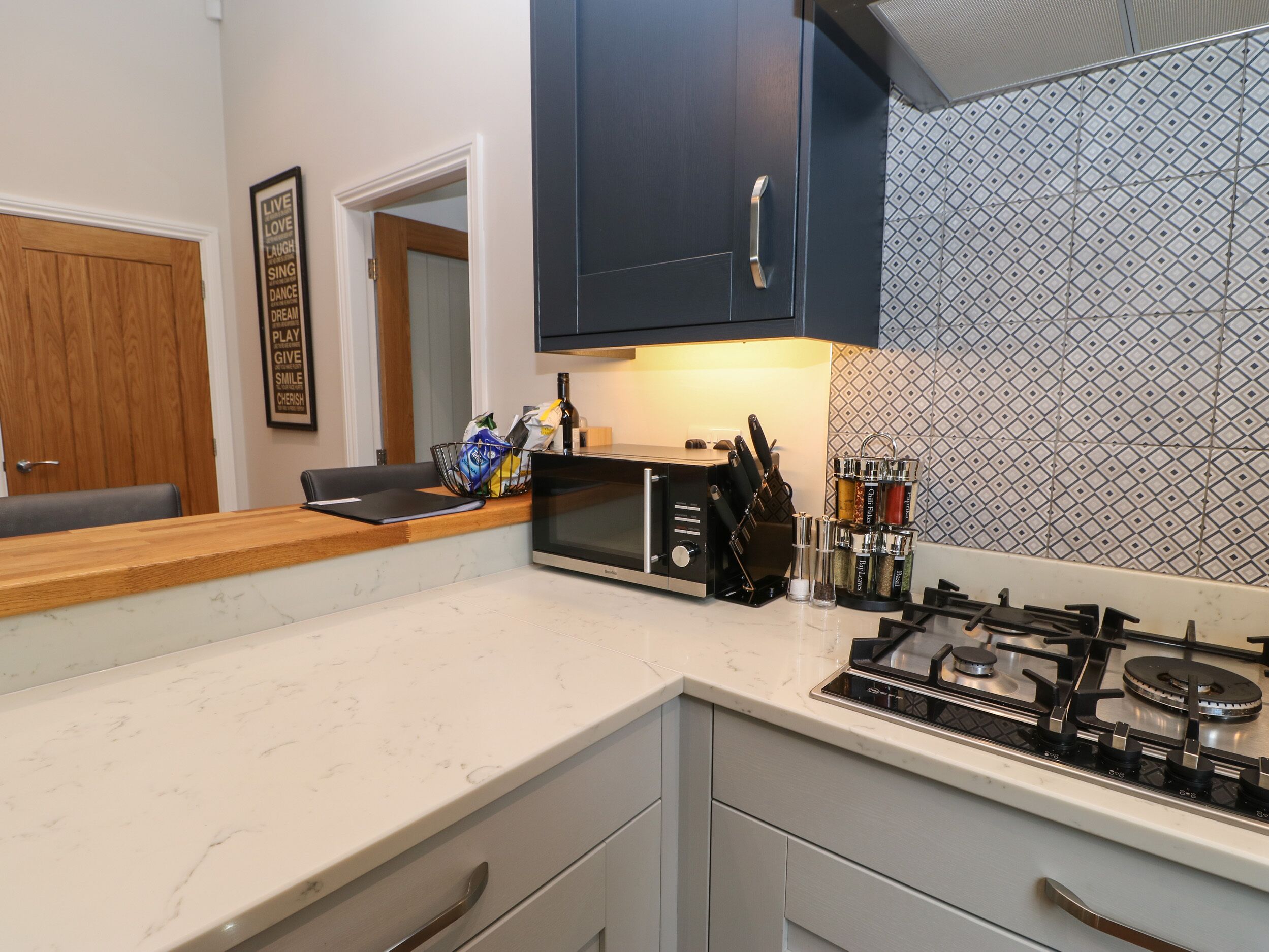 A modern kitchen with a built-in microwave, gas stove, and knife block.