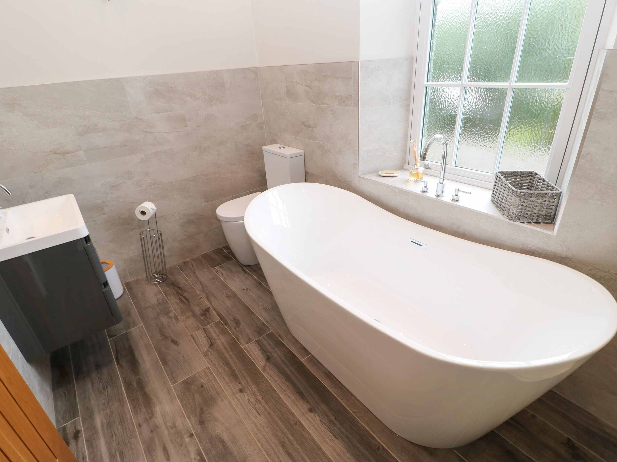 A modern bathroom with a freestanding bathtub, a toilet, and a sink.