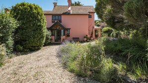 A pink house with a gravel driveway leading to a wooden door. - Heselwood (Lyme Regis)