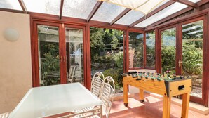 A sunlit patio with a foosball table, a glass table, and chairs. - Heselwood (Lyme Regis)