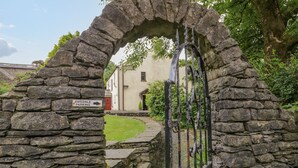 A stone archway leading to a gated entrance with a sign indicating 'Ewedale Parking'. - Ewedale Farm (Ulverston)