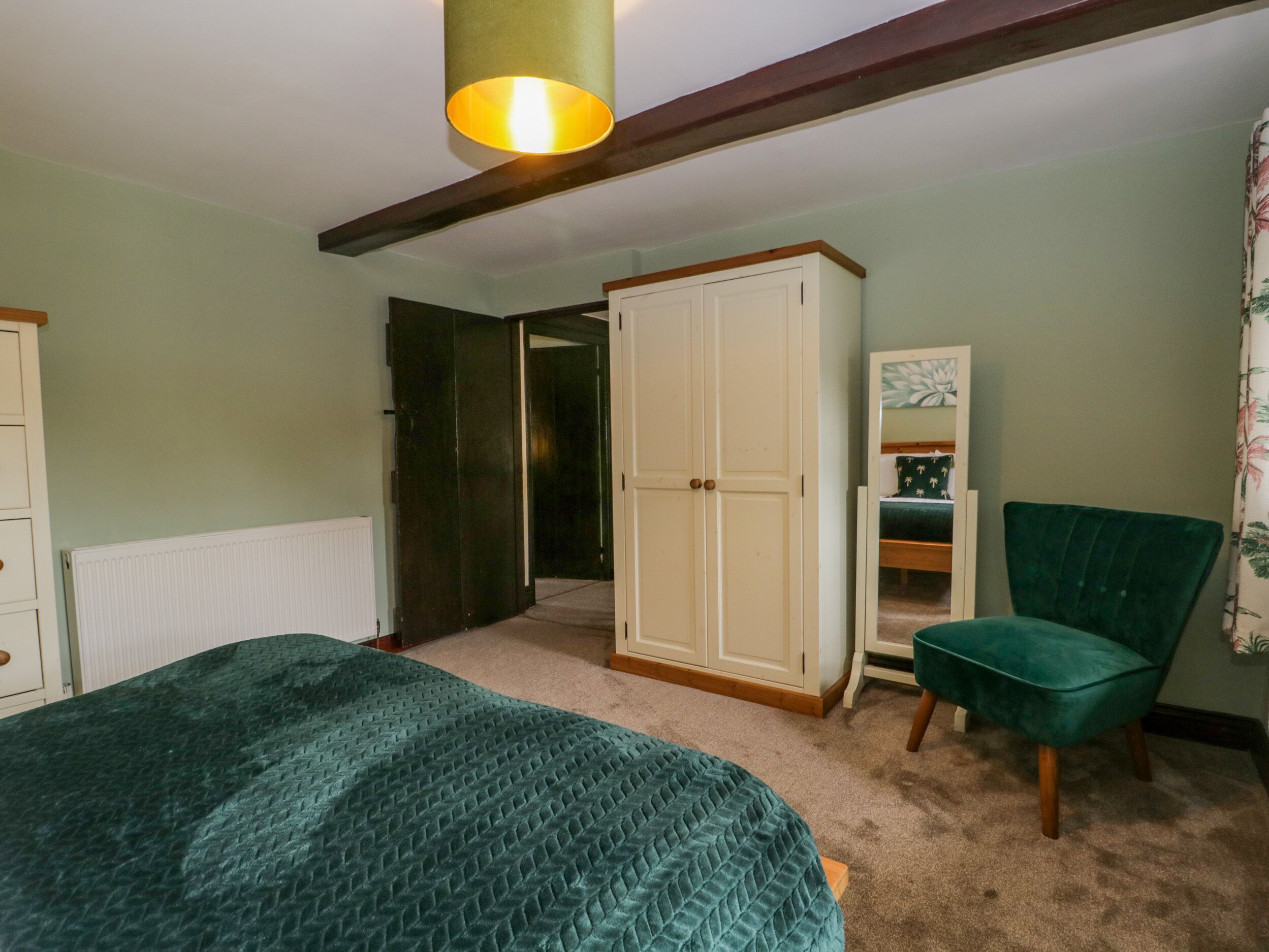Un dormitorio con cama, armario, silla y puerta que da a otra habitación.