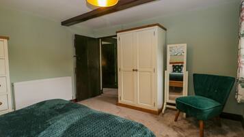 Un dormitorio con cama, armario, silla y puerta que da a otra habitación.
