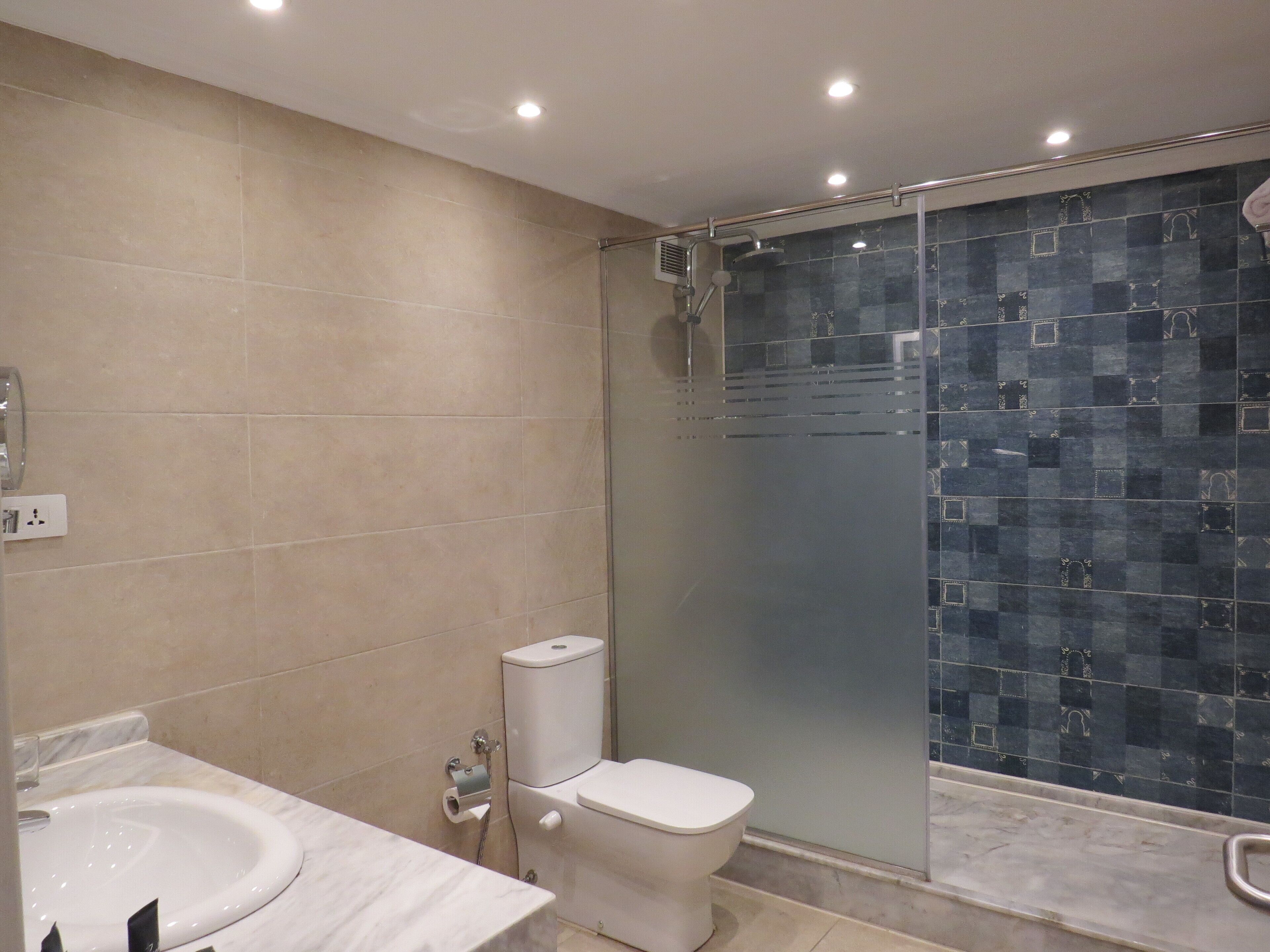 A modern bathroom with a toilet, sink, and glass-enclosed shower.