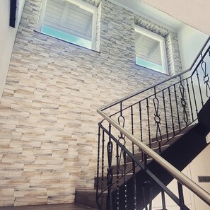 A staircase with a stone wall backdrop and a metal railing.