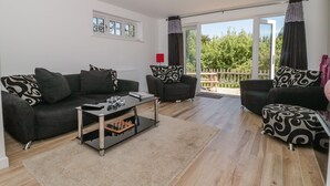 Un salon moderne comprenant un ensemble de canapés, une table basse et une vue sur l’extérieur grâce à de grandes portes-fenêtres coulissantes.