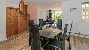 Un espace repas agrémenté d’un escalier en bois, d’une table à manger avec des chaises et offrant une vue sur l’extérieur.
