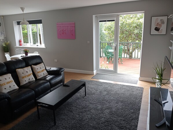 Una sala de estar moderna con un sofá de cuero negro, una mesa de centro y un ventanal corredero que da a un patio exterior.