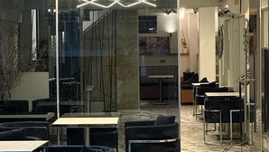 Un interior moderno con separaciones de vidrio, sillas tapizadas en negro y una lámpara de techo de diseño geométrico.