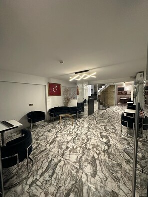 A modern interior with a marble floor, black furniture, and a staircase leading to another area. - Vama Otel Taksim (Istanbul)