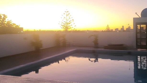 Une piscine sur le toit offrant une vue dégagée sur le coucher du soleil et le panorama de la ville.