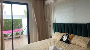 Une chambre d’hôtel avec un lit, une vue sur un balcon agrémenté d’un hamac et un appareil de climatisation.