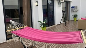 Une pièce avec un hamac, une plante en pot et une porte-fenêtre coulissante.