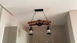 Une cuisine avec des armoires blanches, une hotte de cuisinière en acier inoxydable et un luminaire au plafond original.