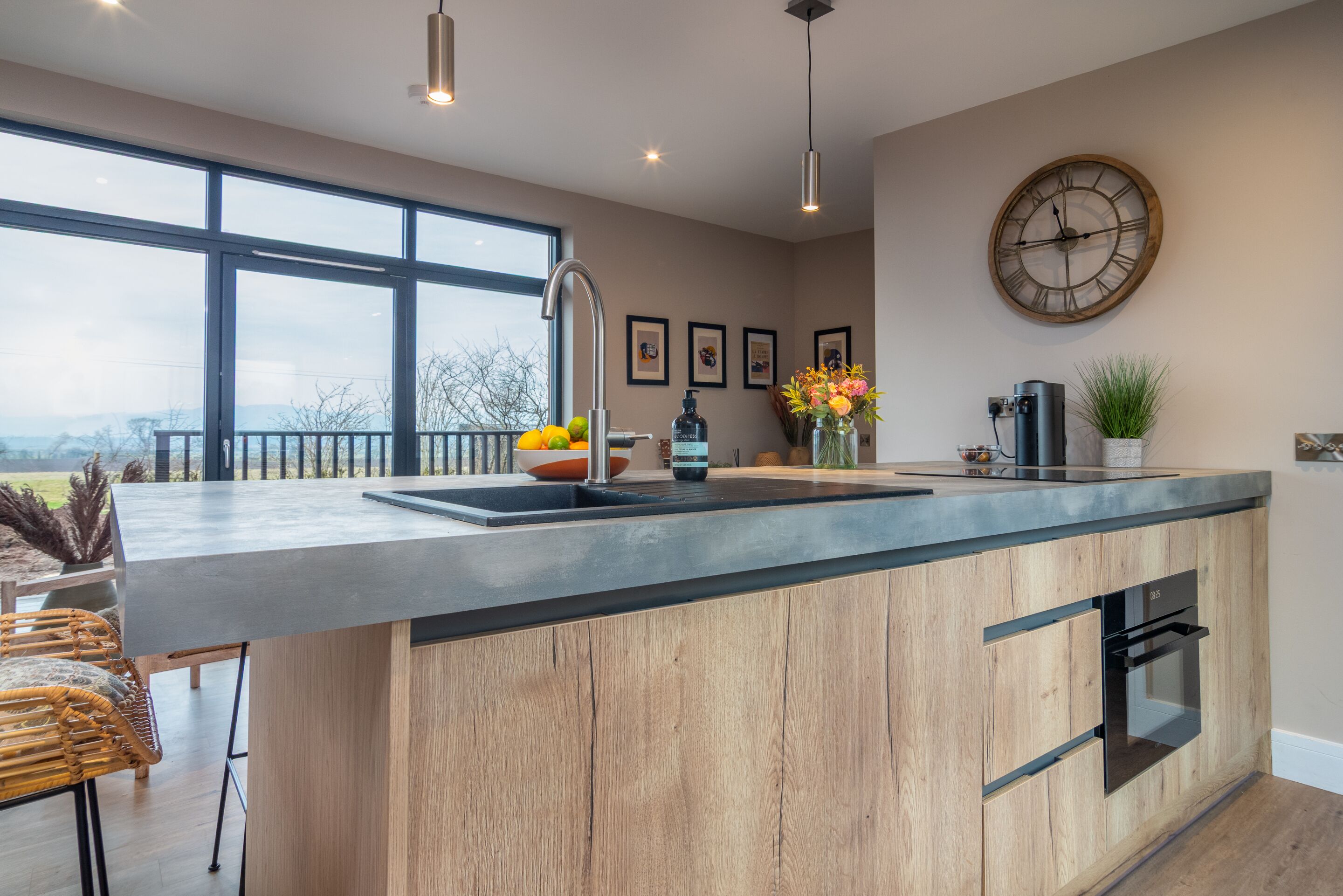 A modern kitchen with a large island, a built-in oven, and a view of the outdoors.