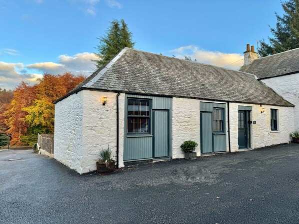 A stone cottage with a gravel driveway and a small garden.