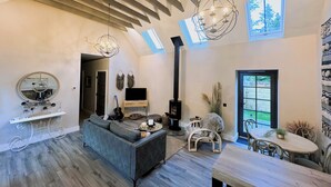 Un salon spacieux avec une cheminée, un canapé, une table à manger et une grande fenêtre.