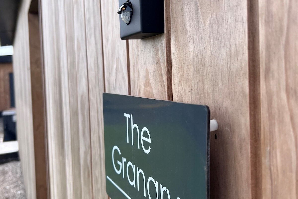A wooden wall with a black light fixture and a sign that reads "The Granary."