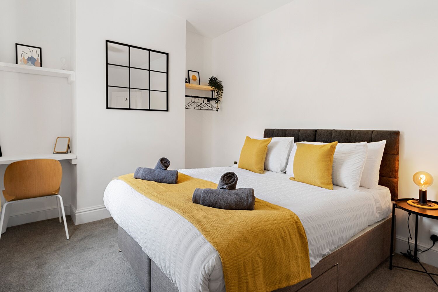 A modern bedroom with a large bed, a desk, and a chair.