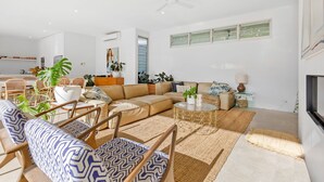 Uma sala de estar moderna com um sofá seccional, uma mesa de centro e uma área de jantar com móveis de vime.