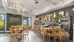 Un interno di ristorante con tavoli e sedie in legno, un menu scritto alla lavagna e un grande cartello con la scritta 'EAT' appeso al muro.