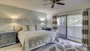 A bedroom with a bed, nightstands, a ceiling fan, and a view through a sliding glass door.