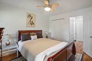 Relax in this classic bedroom with a large bed, ceiling fan, and a nightstand with a lamp.