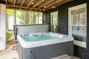 Relax in the hot tub under a covered pergola with a control panel for a soothing experience.