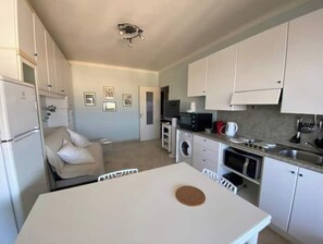 A compact kitchen with white cabinets, a microwave, a coffee maker, and a sink.