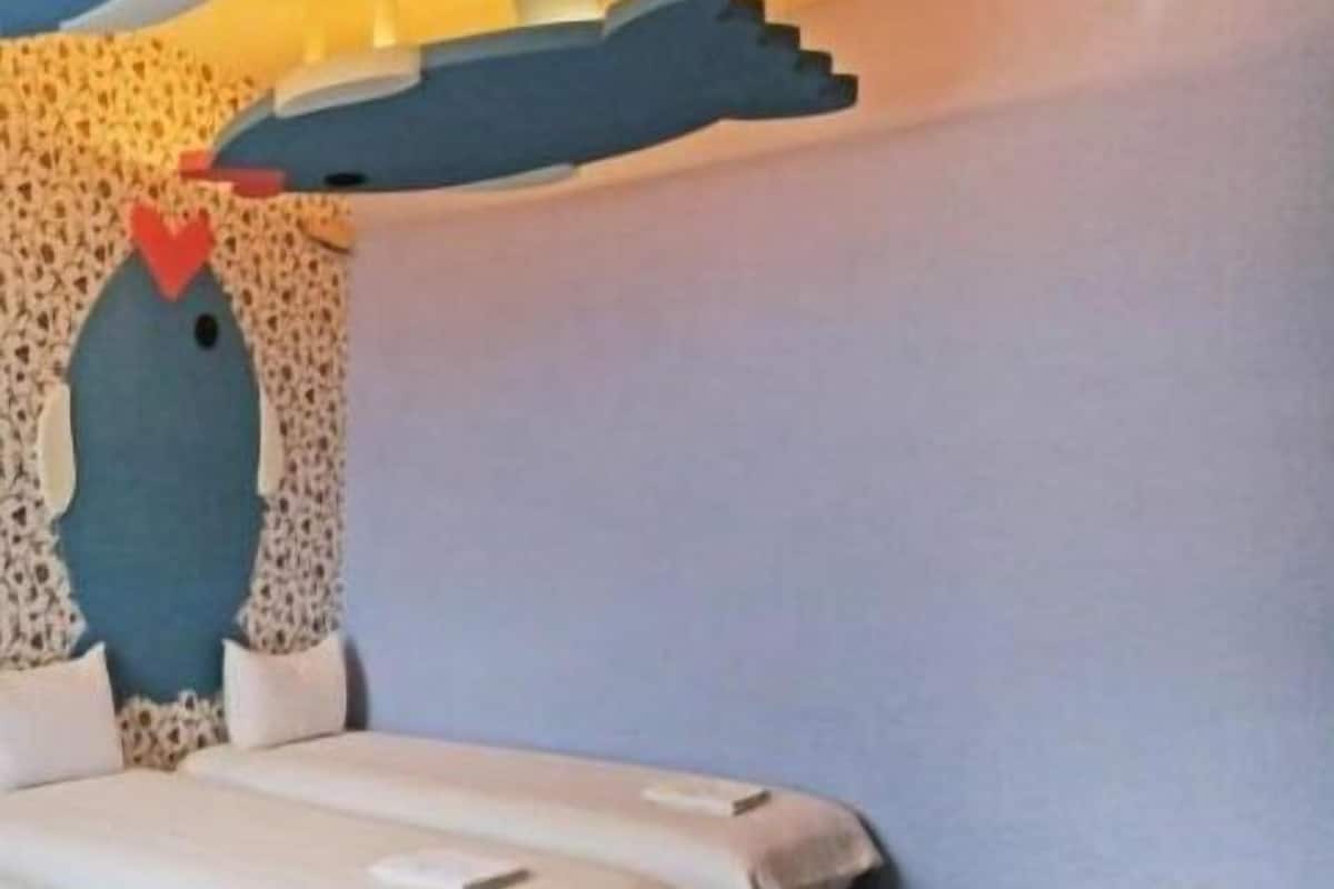 Una habitación con dos camas, una pared azul y una cabeza de pez decorativa en la pared.