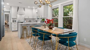 A modern kitchen with white cabinets, a wooden island, and a chandelier. - The Hansel-Modern 4 Bed, 3 Bath Bungalow, Hot Tub (Dallas)